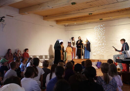 Kinder führen ein Theaterstück auf einer Bühne vor einem Publikum auf